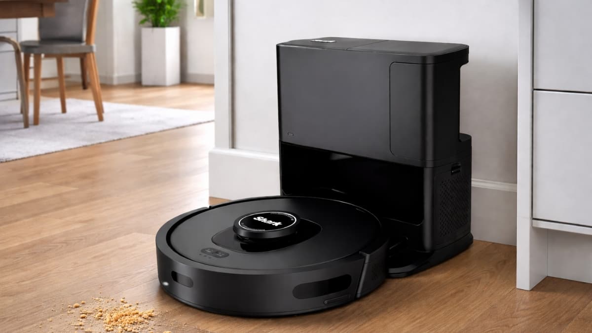 Shark AV2501S AI Ultra robot vacuum docked at its bagless self-emptying base on hardwood floors, cleaning scattered crumbs in a modern home interior.