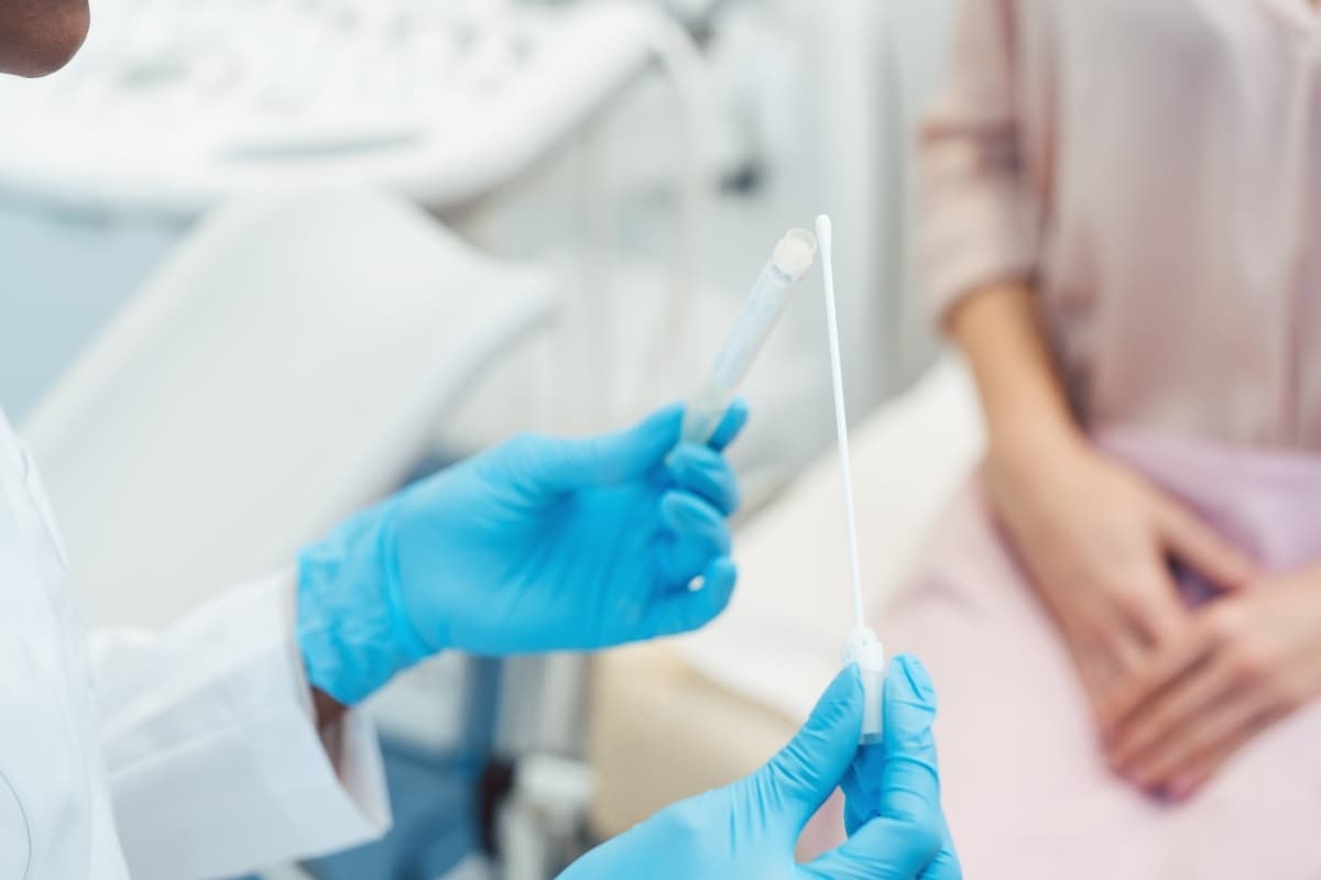 Healthcare professional holding a sterile swab and sample tube during private STI testing in a clinical setting