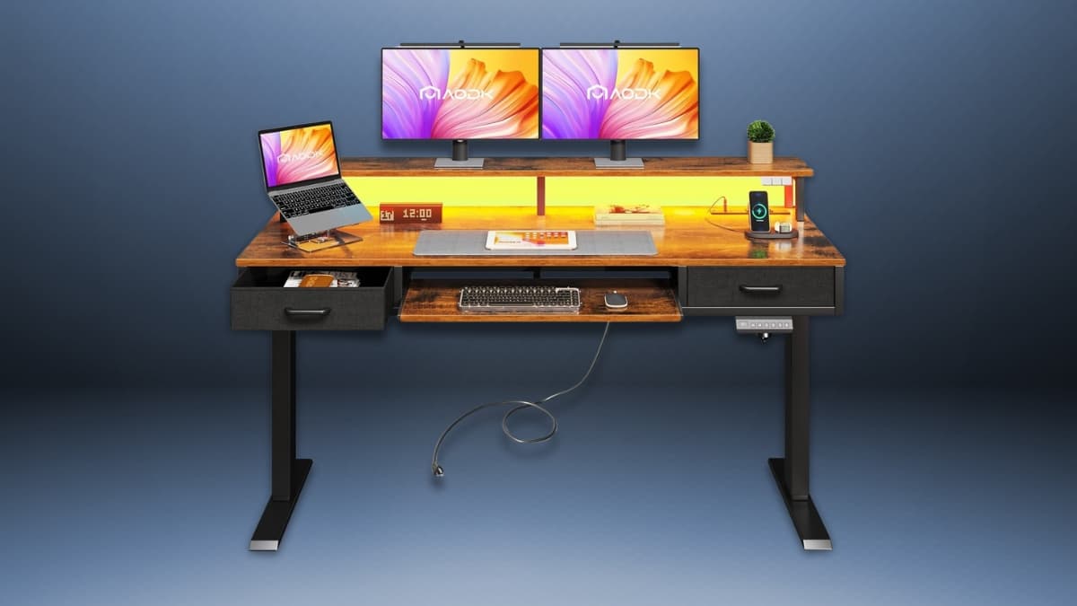 AODK electric standing desk with a wood finish, dual monitors, LED lighting, storage drawers, a keyboard tray, and built-in power outlets for a modern workspace.