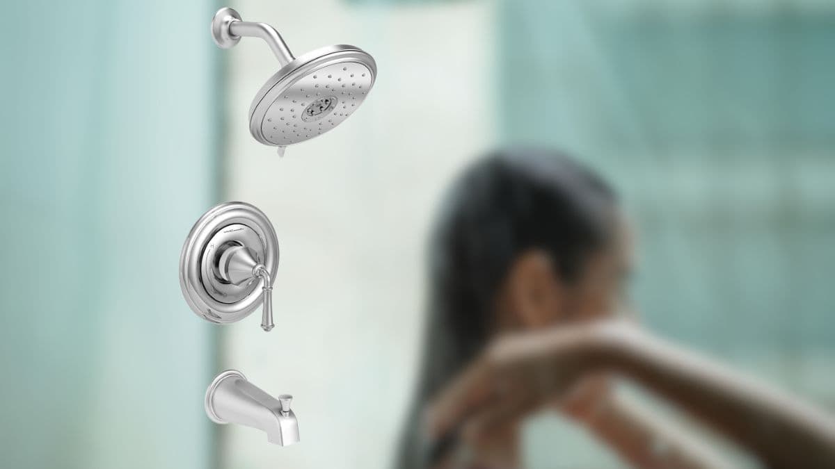 Polished chrome shower trim kit with a round showerhead, single-handle control, and tub spout, set against a blurred bathroom background.