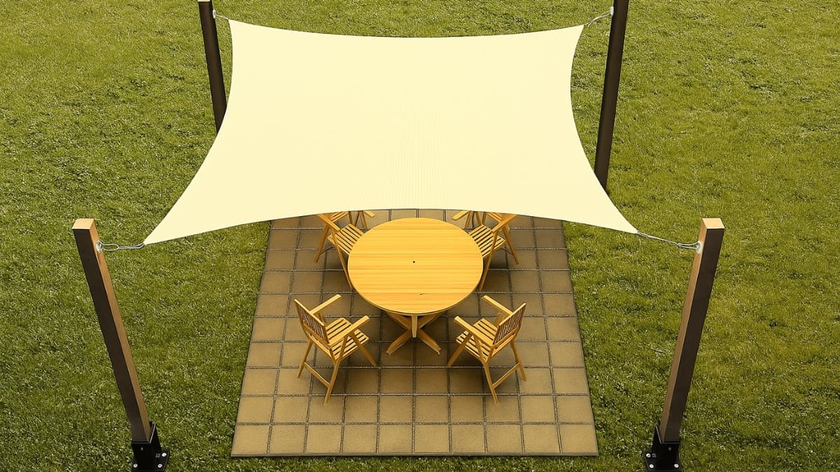 A beige ShadeMart Sun Shade Sail covers a wooden patio table with six chairs on a tiled outdoor space.