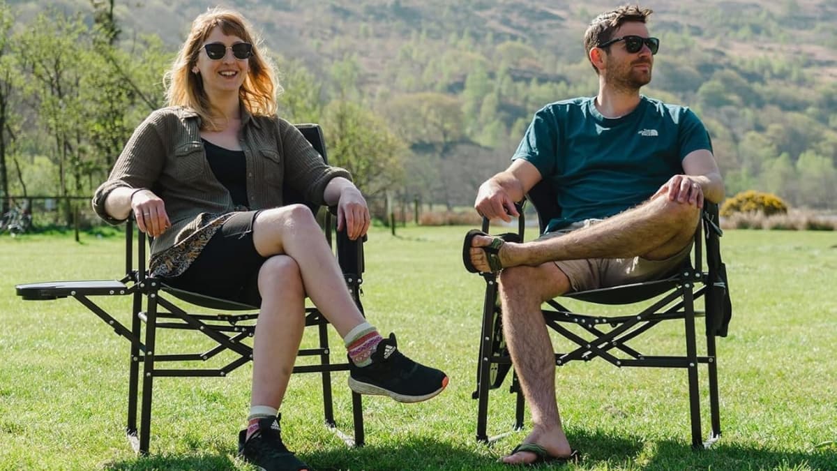 Two people relaxing outdoors in Sunnyfeel camping directors chairs on a grassy field.