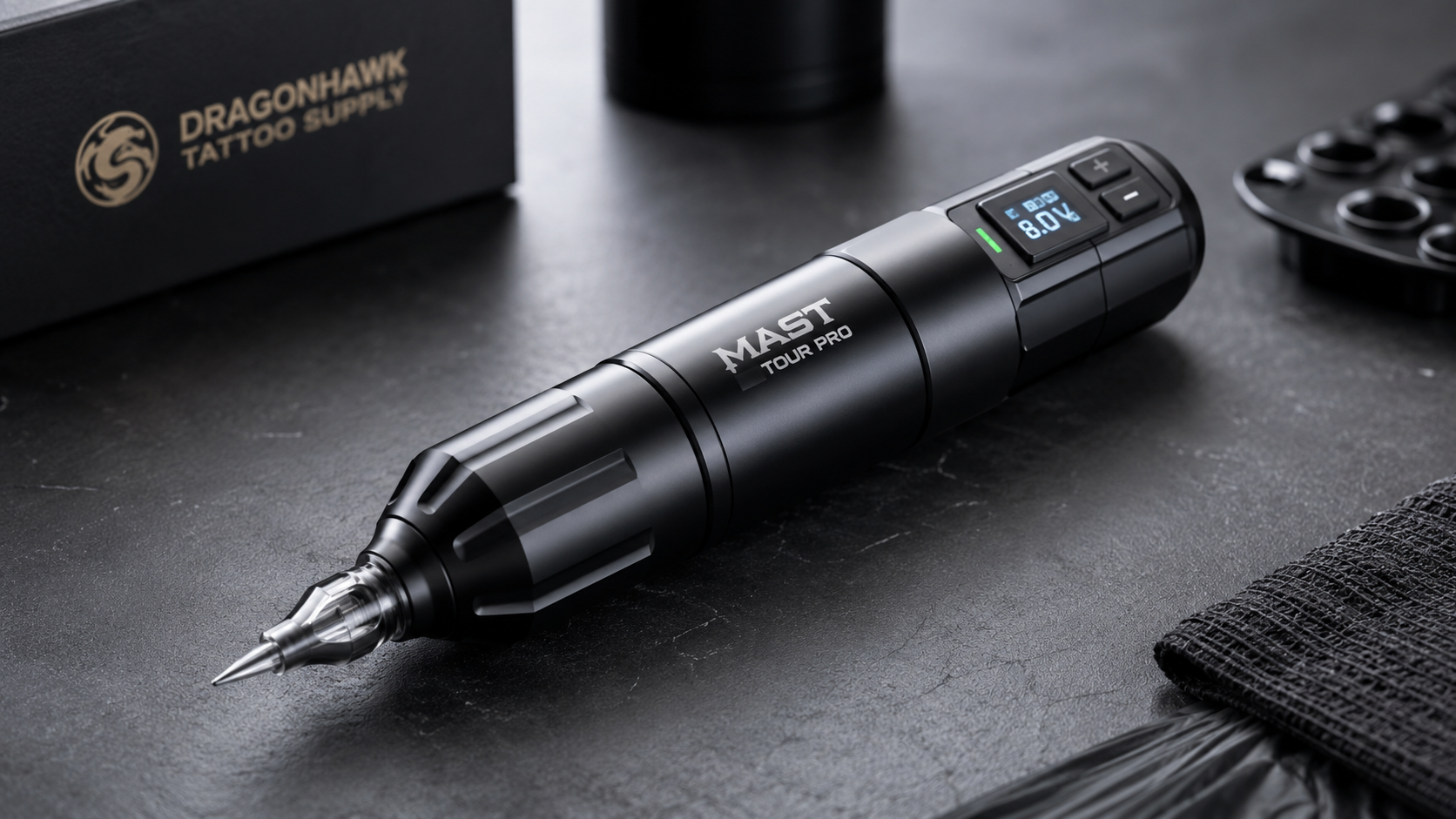 Dragonhawk Mast Tour Pro wireless tattoo pen on a professional black tattoo workstation with digital voltage display and cartridge needle.