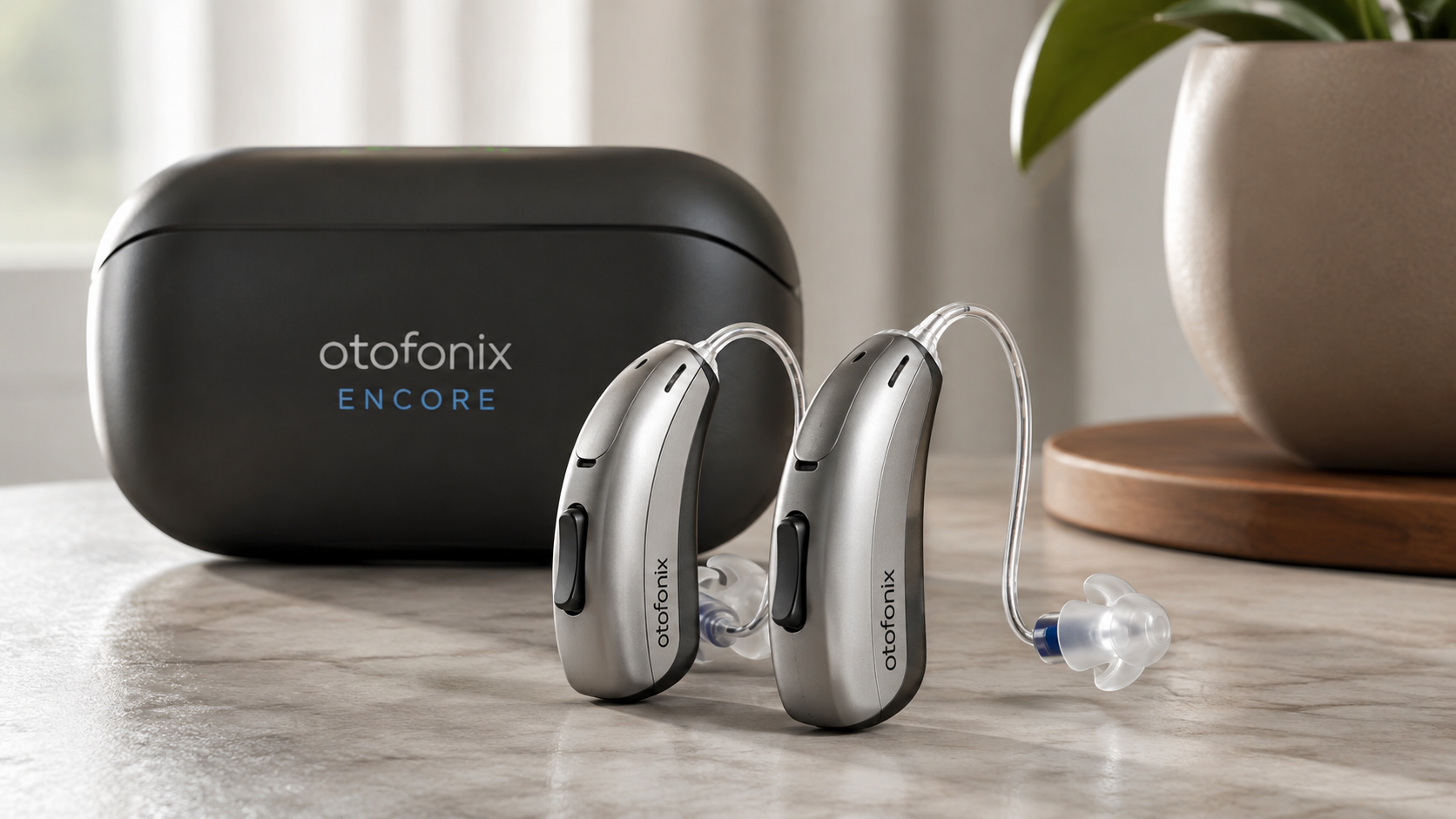 Otofonix Encore rechargeable behind-the-ear hearing aids with charging case on a tabletop, designed for adults with mild to moderate hearing loss.
